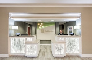 A reception desk with a Holiday Inn sign, two computer monitors, and a security camera. - Holiday Inn & Suites Lake City by IHG (Lake City)