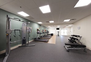 Un gimnasio con cintas de correr, máquinas de pesas y mancuernas.