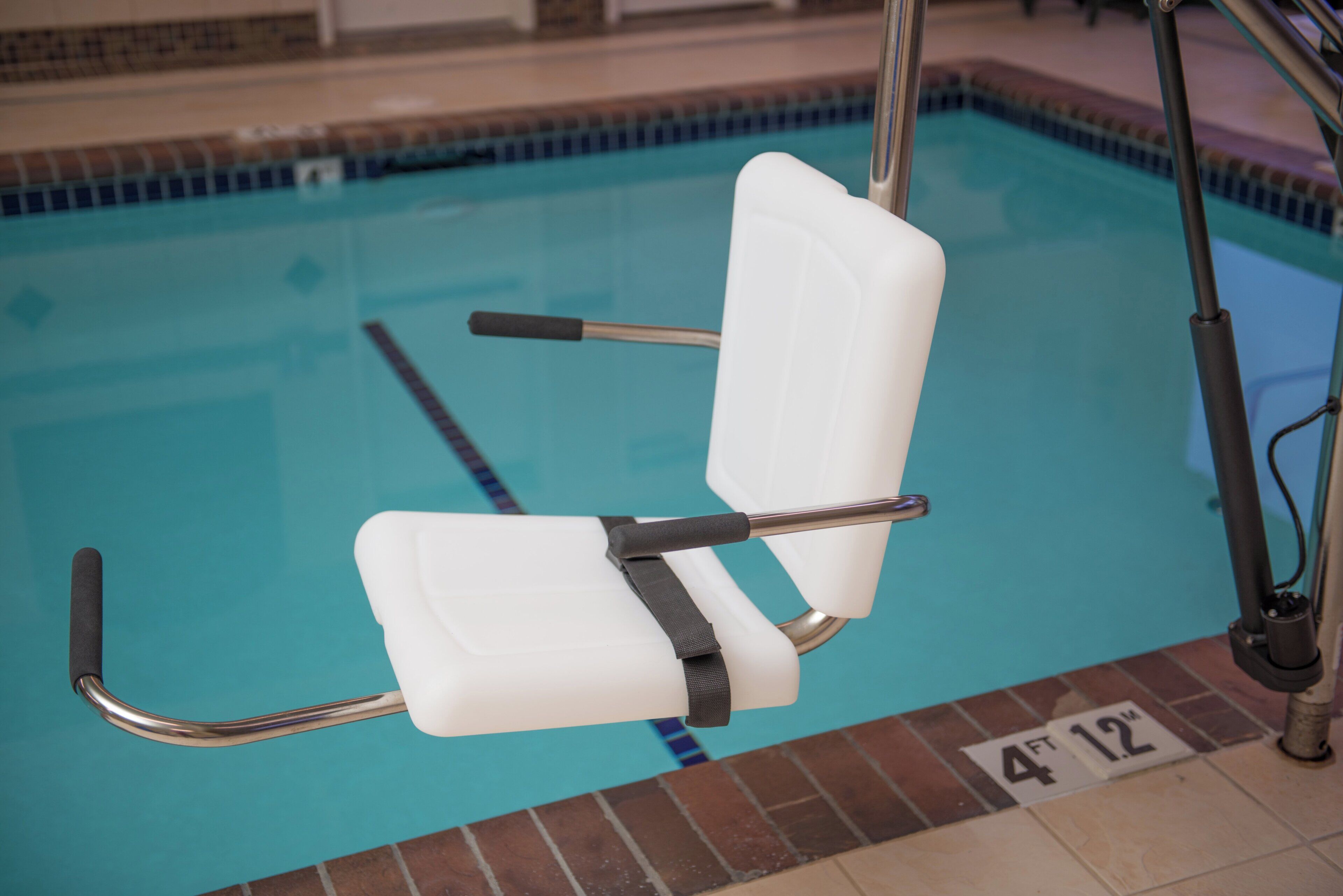 A poolside chair with armrests and a backrest, positioned near the pool's edge.