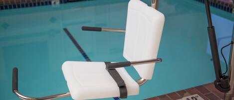 A poolside chair with armrests and a backrest, positioned near the pool's edge.