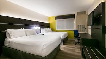 Habitación de hotel con dos camas, un escritorio, una silla, un televisor y una ventana.