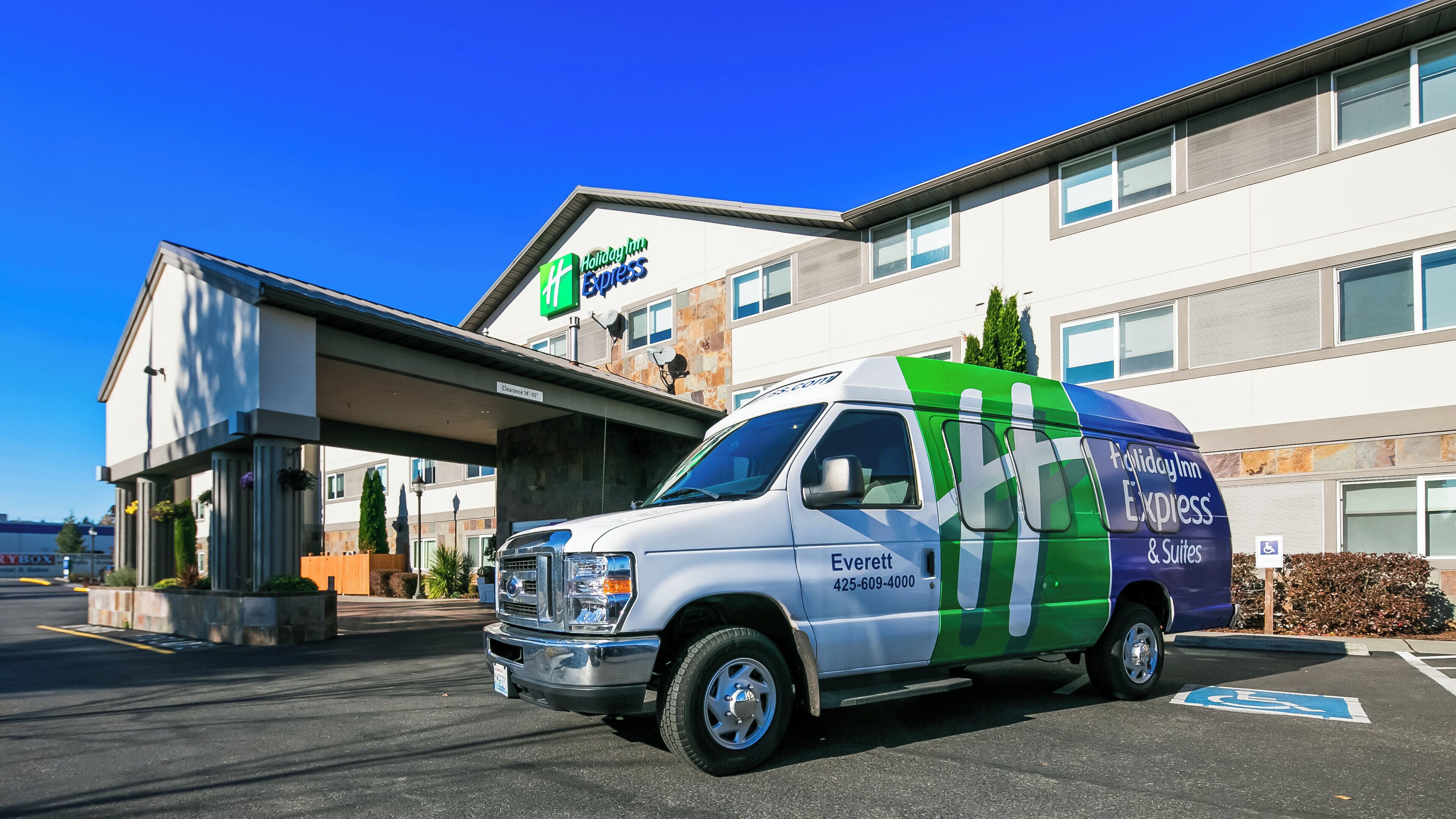 A Holiday Inn Express & Suites hotel with a white and green van parked in front.