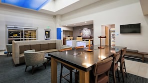 A hotel lobby with a reception desk, seating area, and a television mounted on the wall. - Holiday Inn Express & Suites Everett by IHG (Everett)