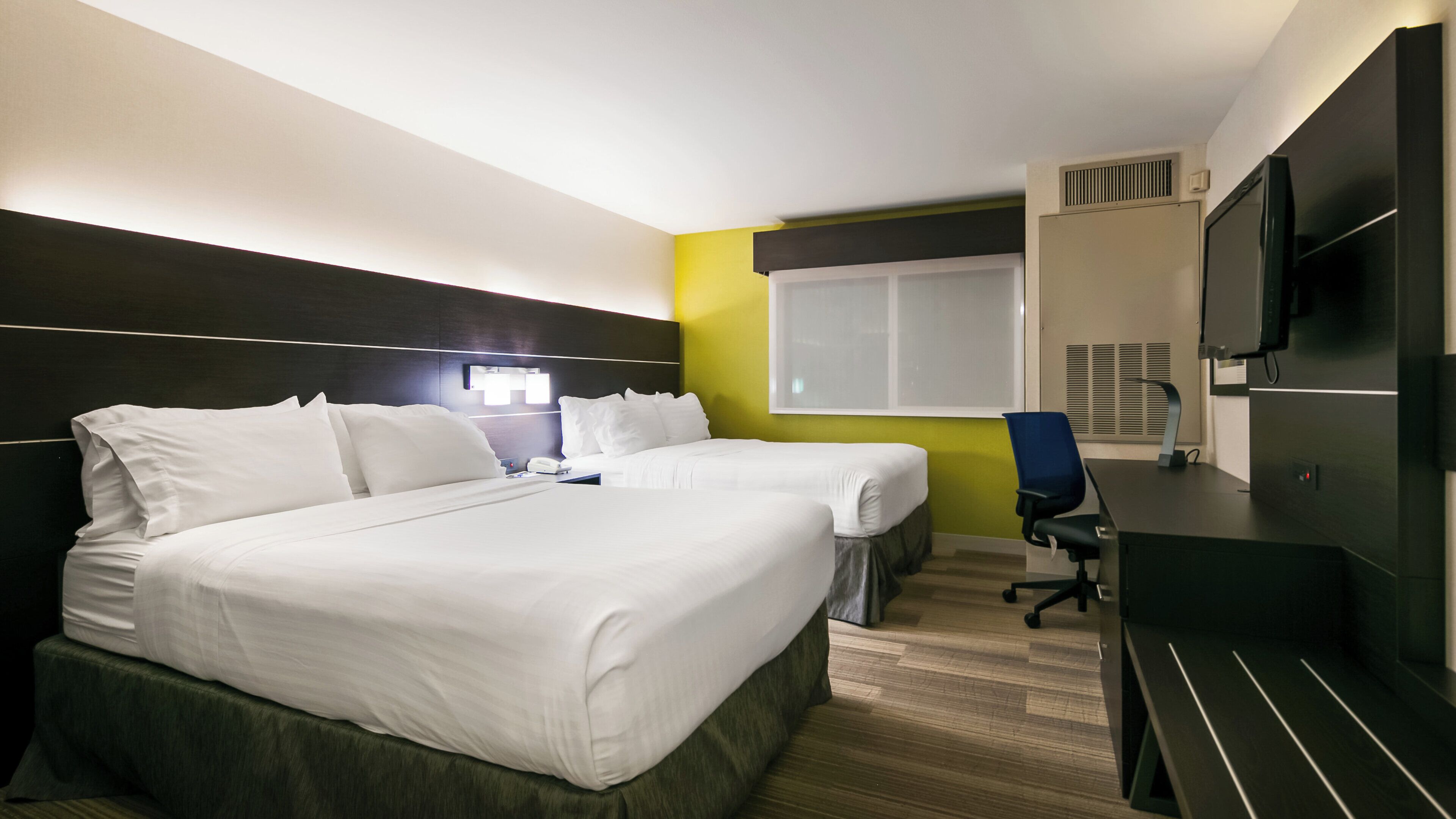 Ett hotellrum med två sängar, ett skrivbord, en stol, en TV och ett fönster.
