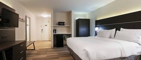 A hotel room with a bed, a desk, a television, and a wardrobe.