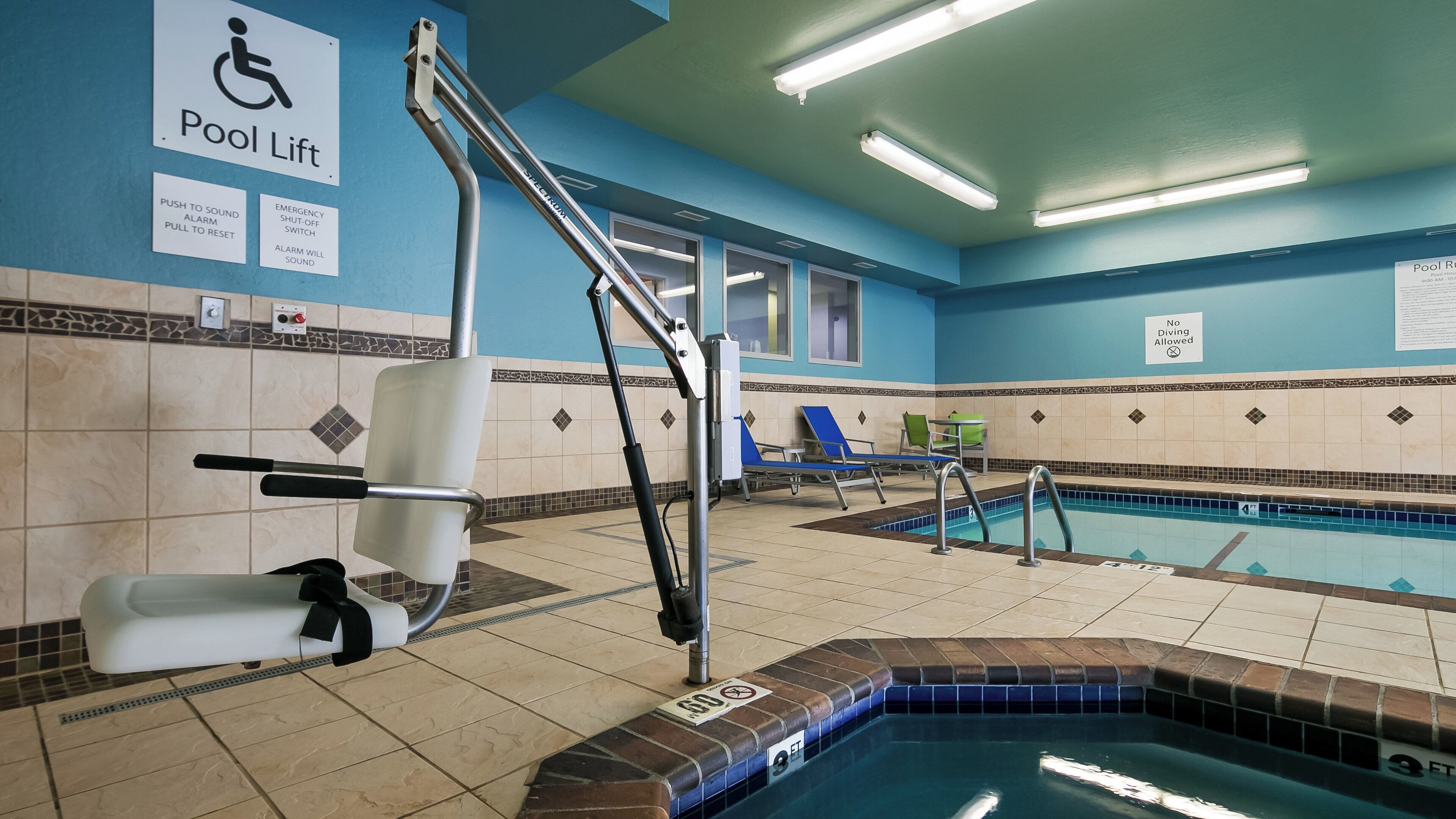 A pool area with a pool lift, chairs, and a sign indicating no driving allowed.
