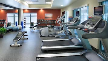 A gym with treadmills, elliptical machines, and free weights.