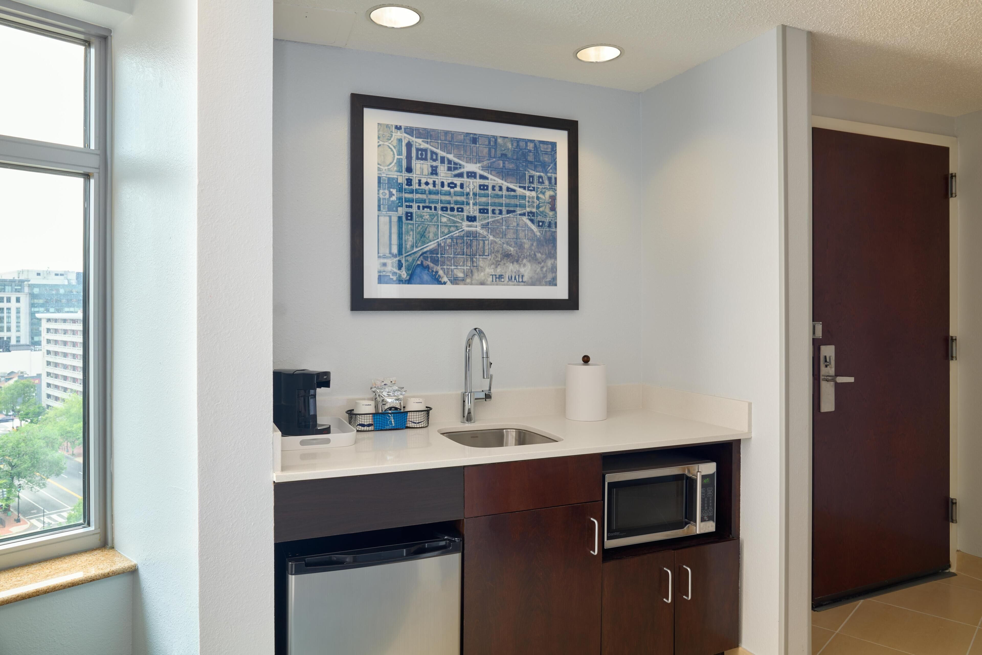 A kitchen with a dishwasher, microwave, sink, and a framed map on the wall.