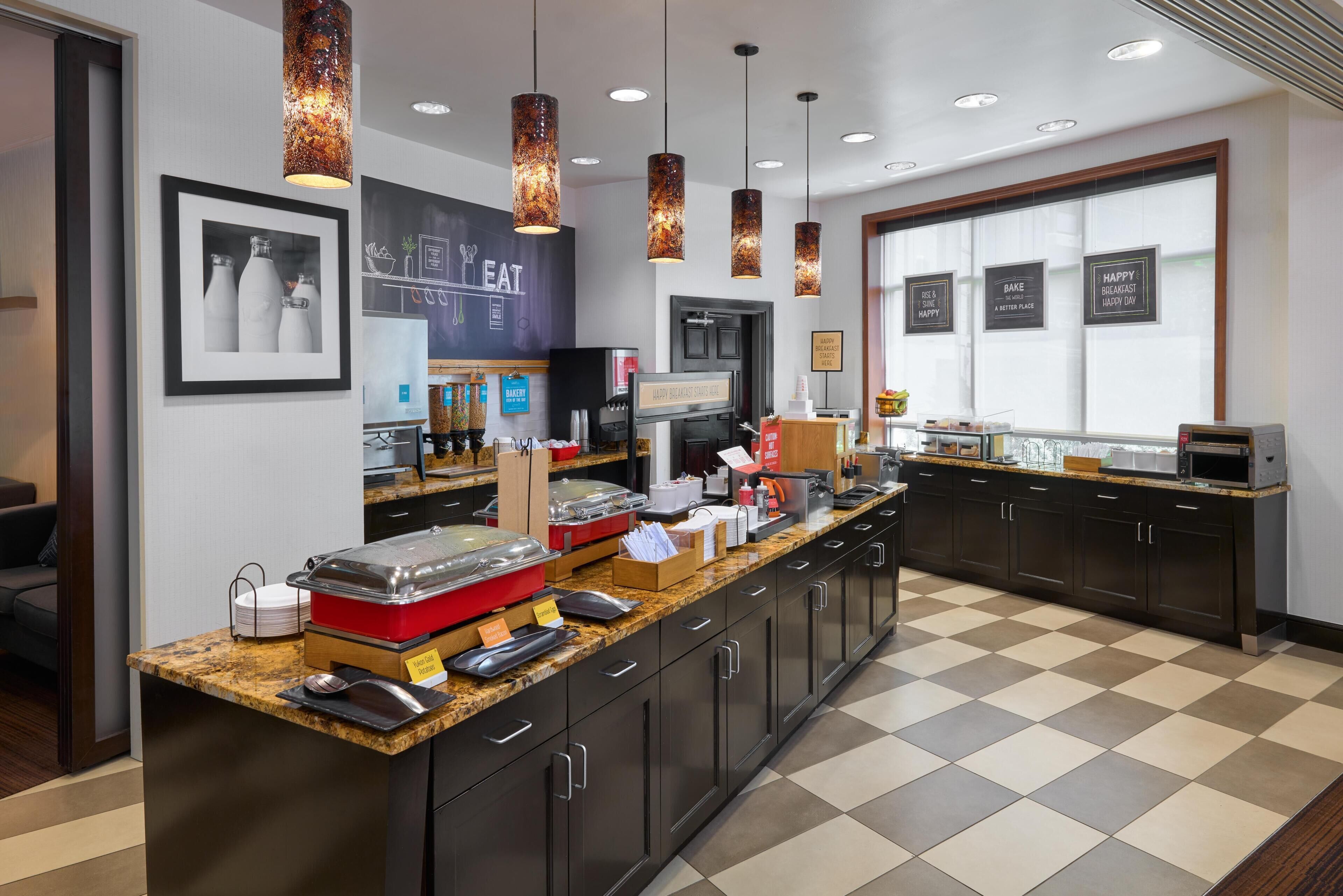 A breakfast bar with food dispensers, a coffee machine, and a chalkboard menu.