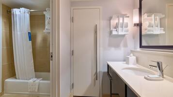 A bathroom with a shower, toilet, sink, and towel storage.