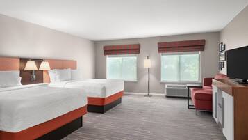 A hotel room with two beds, a desk, a chair, and a television.