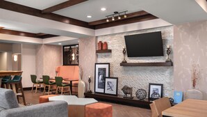 A modern living room with a fireplace, a flat-screen TV, and a dining area with chairs and a table. - Hampton Inn & Suites Fresno (Fresno)