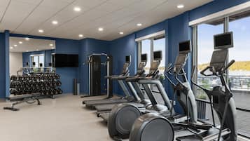 Une salle de sport équipée de tapis de course, de vélos elliptiques et de matériel de musculation.