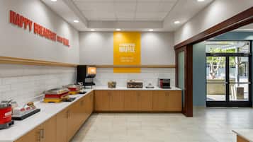 Un espace cuisine moderne doté d’un bar pour prendre le petit-déjeuner, d’un appareil à gaufres et d’une machine à café.