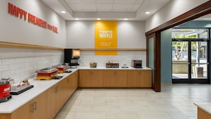 A modern kitchen area with a breakfast bar, a waffle station, and a coffee machine. - Hampton Inn & Suites Bremerton (Bremerton)