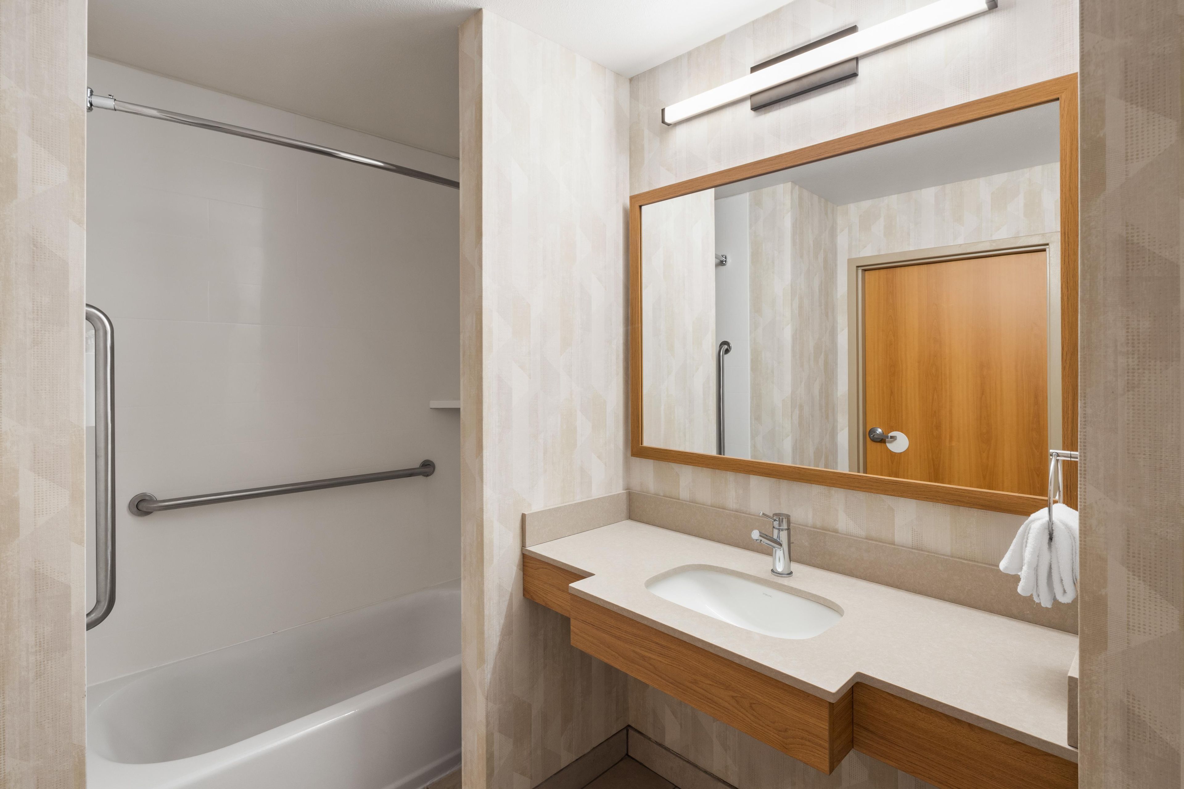 A modern bathroom with a bathtub, a vanity with a sink, and a mirror.