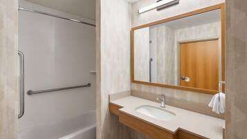 A modern bathroom with a bathtub, a vanity with a sink, and a mirror.