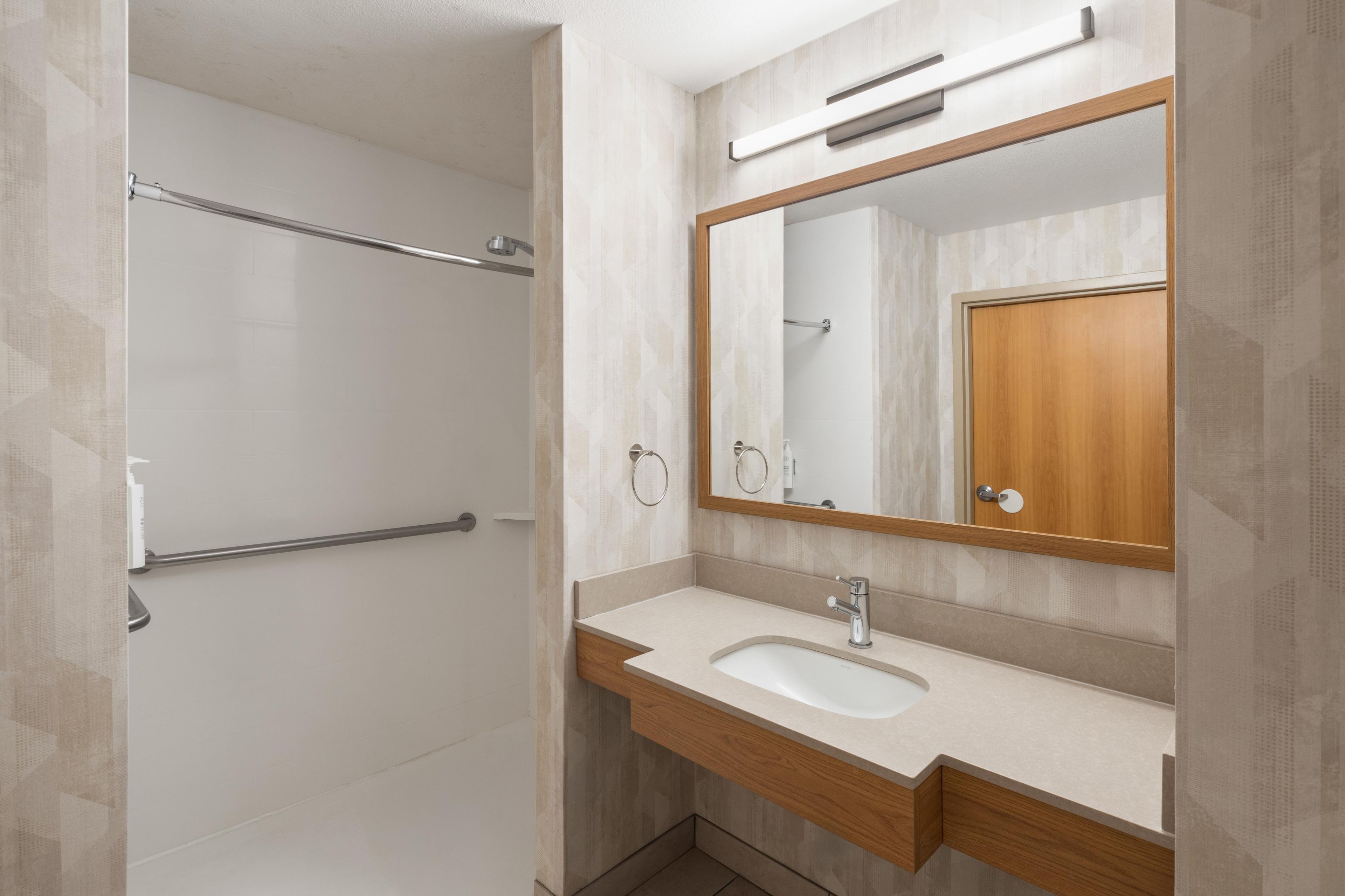 Uma casa de banho moderna com chuveiro, lavatório e espelho.