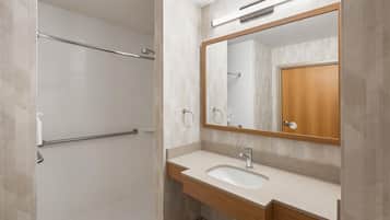 Uma casa de banho moderna com chuveiro, lavatório e espelho.