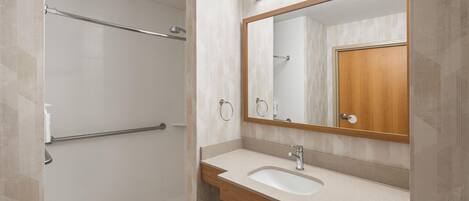 A modern bathroom with a shower, a sink, and a mirror.