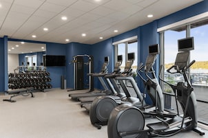 Un gimnasio con cintas de correr, elípticas y equipo de levantamiento de pesas.