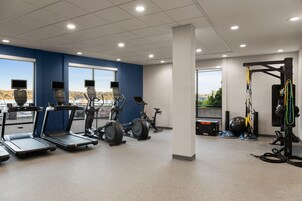 Un gimnasio con cintas de correr, elípticas y un entrenador TRX.