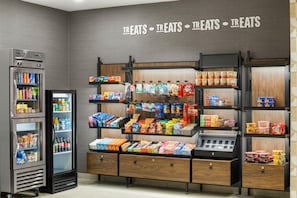 A snack display with various packaged foods and a refrigerated section with beverages. - Hampton Inn & Suites Bremerton (Bremerton)