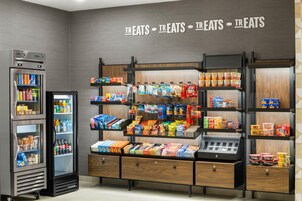 Exposição de lanches com diversos alimentos embalados e uma área refrigerada com bebidas.