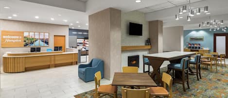 Un hall de hotel con mostrador de recepción, zona de estar y chimenea.