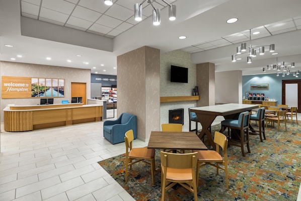 A hotel lobby with a reception desk, seating area, and a fireplace.