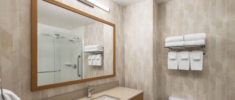 A bathroom with a wooden vanity, a sink, a mirror, a glass shower enclosure, and a toilet.