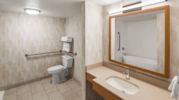 A bathroom with a toilet, sink, and mirror.