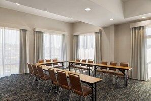 A conference room with a long table and chairs, large windows with curtains, and a carpeted floor. - Hampton Inn & Suites Bremerton (Bremerton)