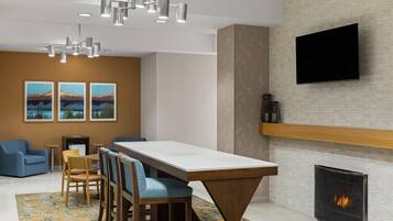 A modern interior with a dining area, seating, a fireplace, and a flat-screen TV mounted on the wall.