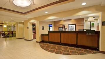 A reception area with a wooden reception desk, a patterned carpet, and a chandelier.