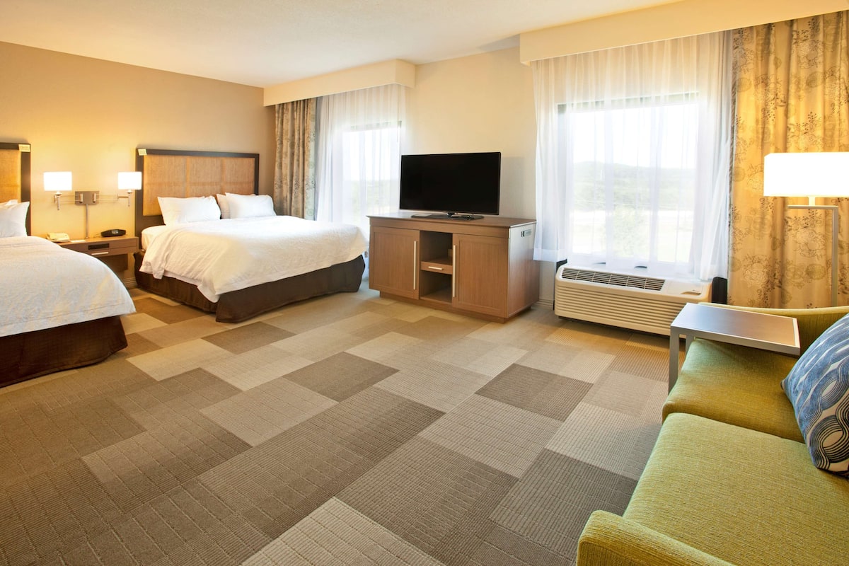 Une chambre d’hôtel avec deux lits, une télévision, un bureau et un canapé.