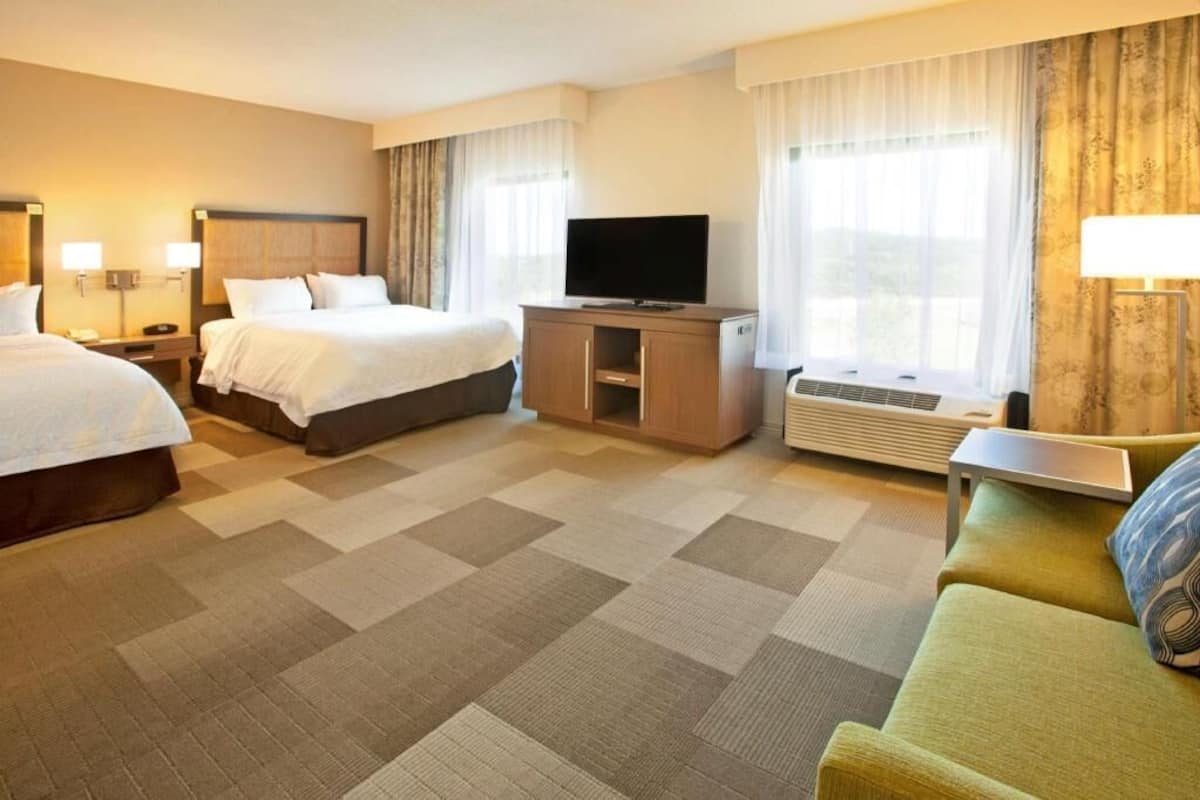 Une chambre d’hôtel avec deux lits, une télévision, un bureau et un canapé.