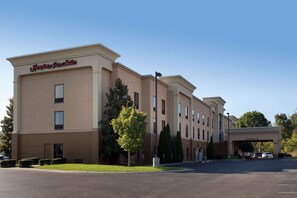 Ein Hampton Inn Suites Gebäude mit freiem Eingang, Parkplatz und einem Schild mit der Aufschrift 'Clearance 18'.