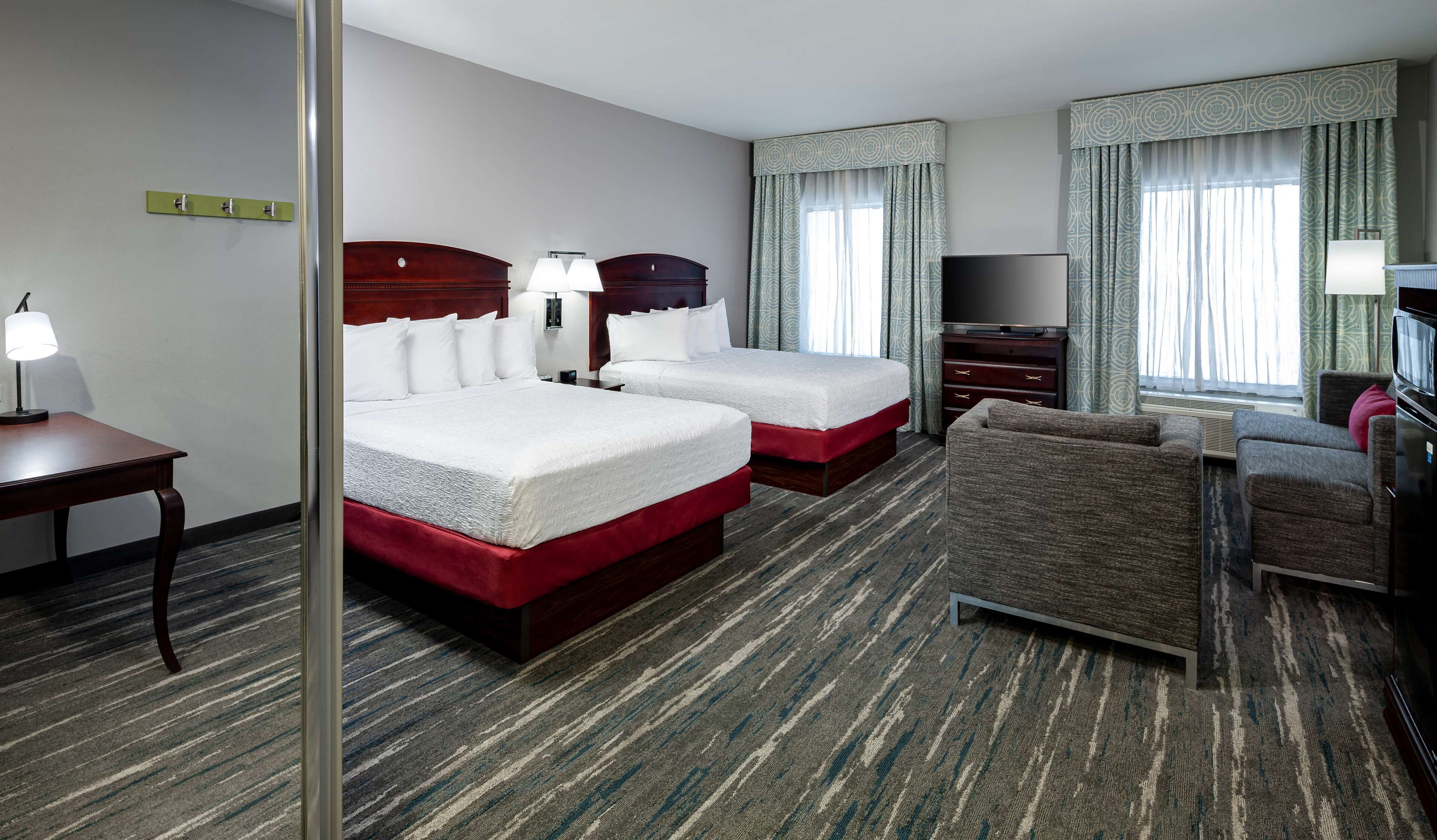 A hotel room with two beds, a TV, a desk, and a chair.