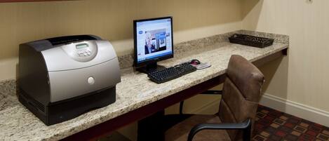 A home office setup with a desktop computer, printer, and office chair.