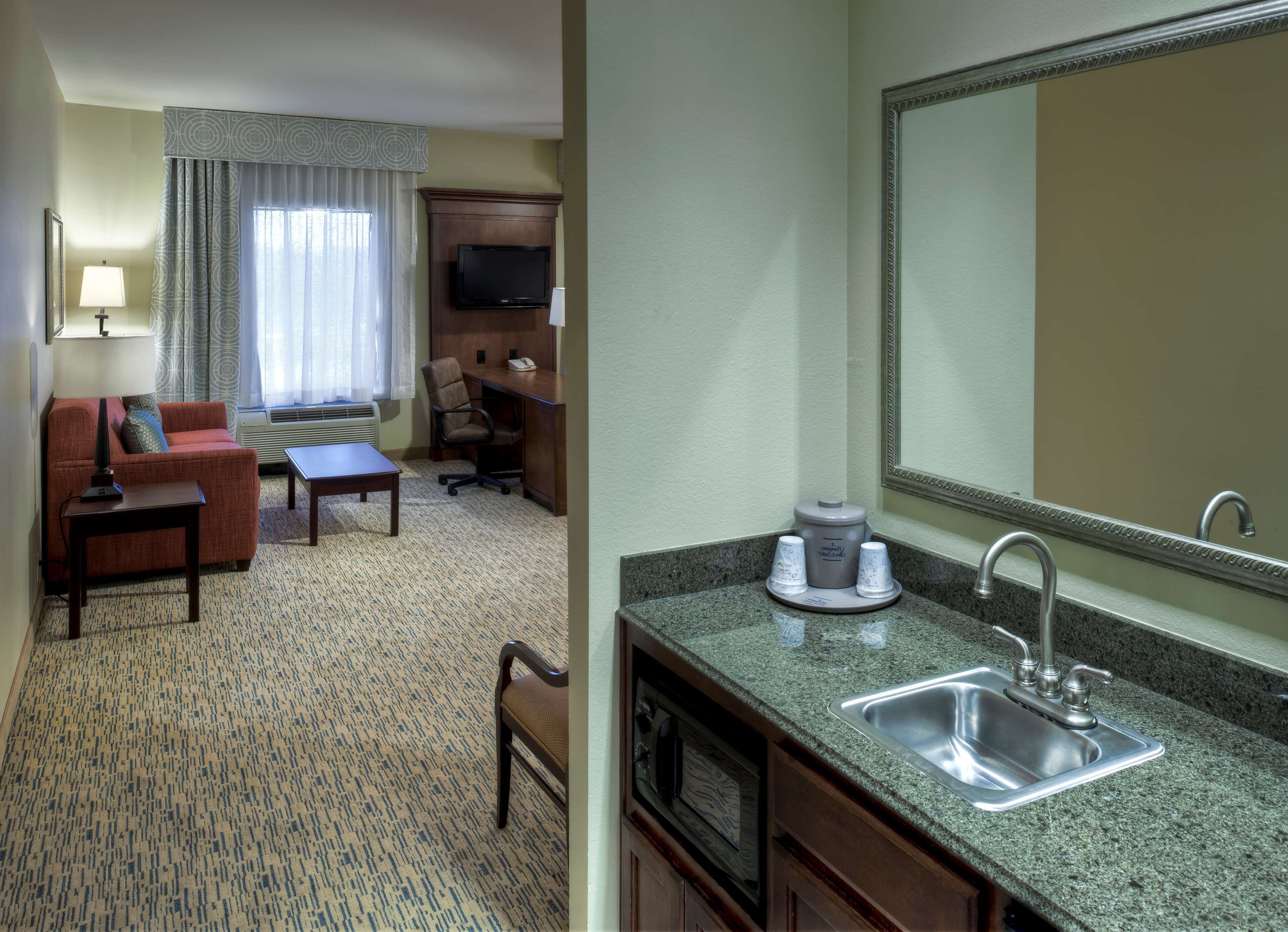 Una habitación de hotel con sala de estar, kitchenette y baño.
