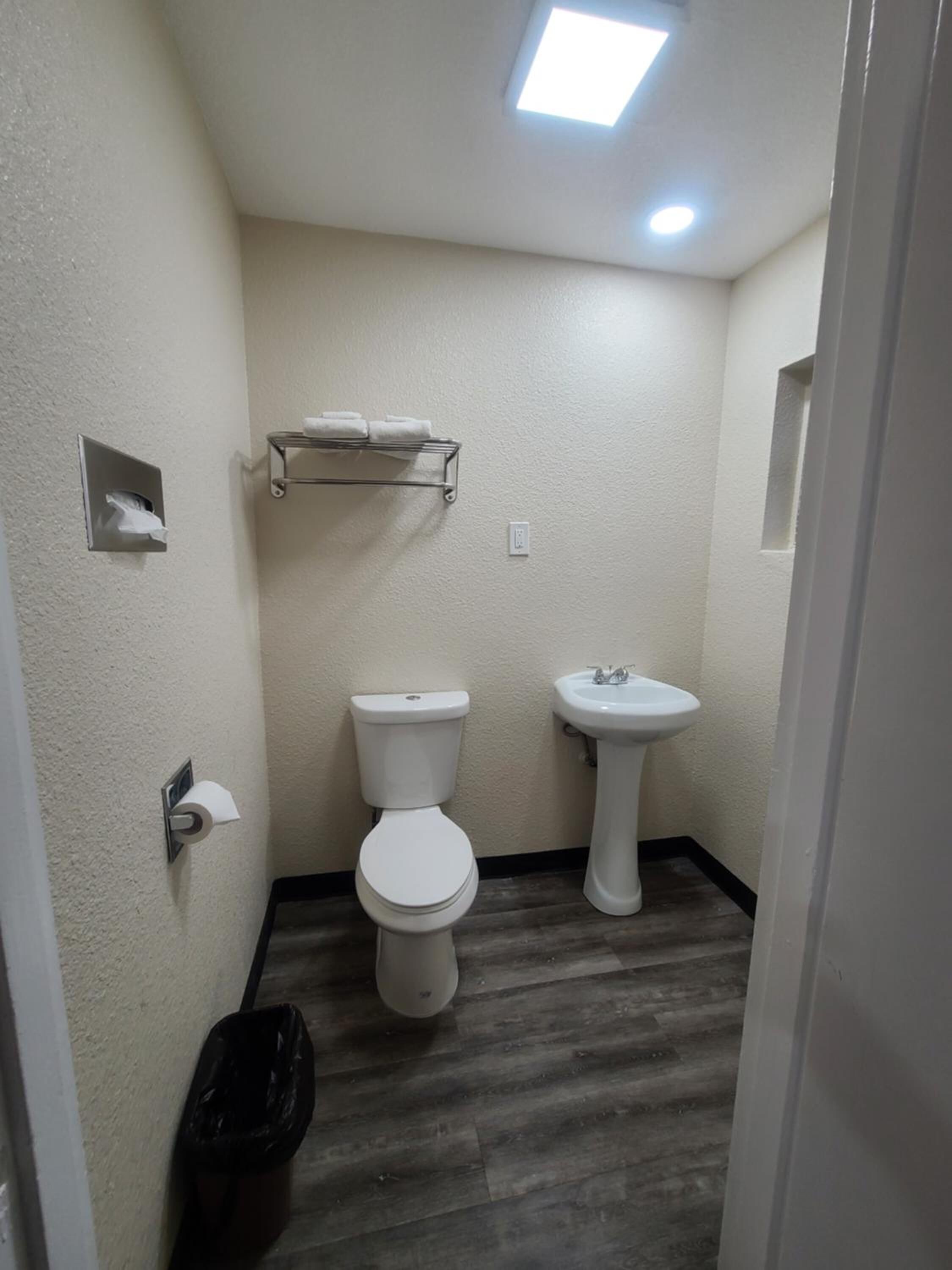 Un baño pequeño con inodoro, lavamanos y perchero para toallas.