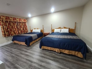 A hotel room with two beds, wooden headboards, and a patterned curtain. - Majestic Inn And Suites (Klamath Falls)
