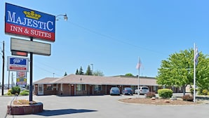 A Majestic Inn & Suites with a clear sky, a parking lot, and an American flag. - Majestic Inn And Suites (Klamath Falls)