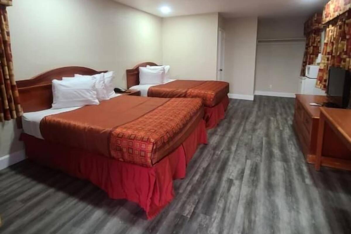 A hotel room with two beds, a desk, and a television.