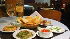 Une table à manger avec différents plats, une bouteille de vin et un verre de vin blanc.