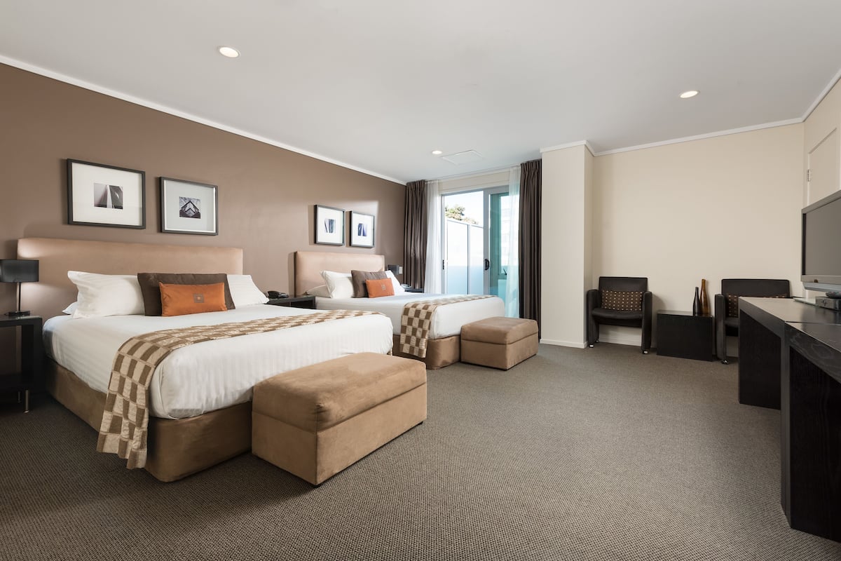 A hotel room with two beds, a desk, and a chair.