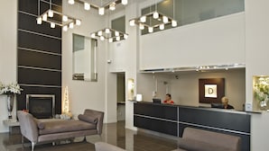 A hotel reception area with a modern design, featuring a reception desk, seating area, and a fireplace. - Hotel on Devonport (Tauranga)