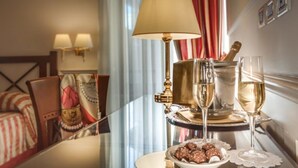 A hotel room with a dining table set for two, featuring a bottle of champagne, two glasses, and a plate of chocolates. - Palazzo Cardinal Cesi (Rome)
