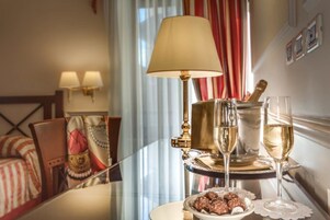 Ein Hotelzimmer mit Esstisch, gedeckt für zwei Personen, mit einer Champagnerflasche, zwei Gläsern und einer Schokoladentafel.